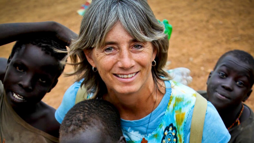 Carolyn Figlioli smiling outdoors with children from the South Sudan children's home